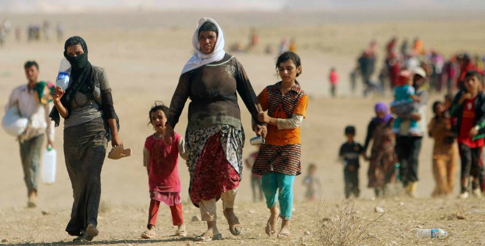 Displaced people from the minority Yazidi sect, fleeing violence from forces loyal to the Islamic State in Sinjar town, walk towards the Syrian border, on the outskirts of Sinjar mountain, near the Syrian border town of Elierbeh of Al-Hasakah Governorate August 11, 2014. Islamic State militants have killed at least 500 members of Iraq's Yazidi ethnic minority during their offensive in the north, Iraq's human rights minister told Reuters on Sunday. The Islamic State, which has declared a caliphate in parts of Iraq and Syria, has prompted tens of thousands of Yazidis and Christians to flee for their lives during their push to within a 30-minute drive of the Kurdish regional capital Arbil. Picture taken August 11, 2014. REUTERS/Rodi Said (IRAQ - Tags: CIVIL UNREST POLITICS SOCIETY)