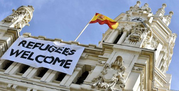 A Spanish flag flies above a banner reading "Refugees Welcome" hanging on the facade of the Cibeles Palace, the Madrid City Hall, on September 7, 2015. The numbers of migrants have spiked since September 4, 2015, when Austria and Germany threw open their borders and eased travel restrictions to allow in thousands who had made it to Hungary, which has balked at the influx.    AFP PHOTO/ GERARD JULIEN