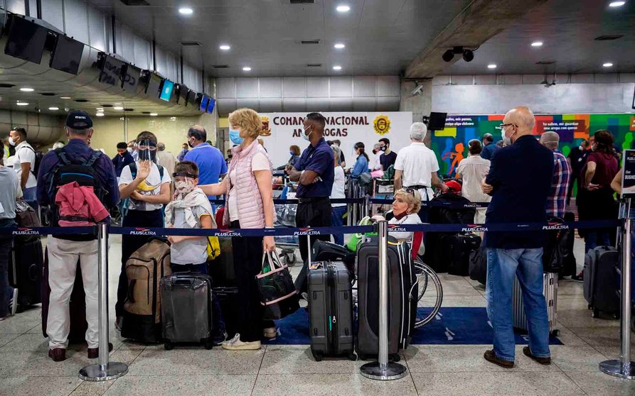 AME807. MAIQUIETIA (VENEZUELA), 04/07/2020.- Un grupo de personas hacen fila para registrar su equipaje en el Aeropuerto Internacional Simón Bolívar, este sábado en Maiquetía (Venezuela). Un total de 376 pasajeros, casi todos europeos, salieron este viernes de Caracas con destino a Madrid en el cuarto vuelo de repatriación que organiza la Embajada de España en Venezuela. EFE/MIGUEL GUTIERREZ
