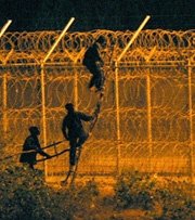 Ciudadanos subsaharianos intentan saltar la valla en Ceuta.