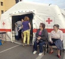 Varias personas esperan para recibir asistencia en un campamento en Lorca.