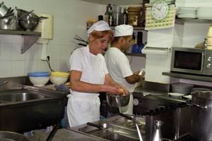 Dos inmigrantes trabajan en la cocina de un restaurante español.