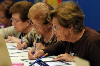 Tres mujeres mayores participan en una de las actividades de un taller de arte.