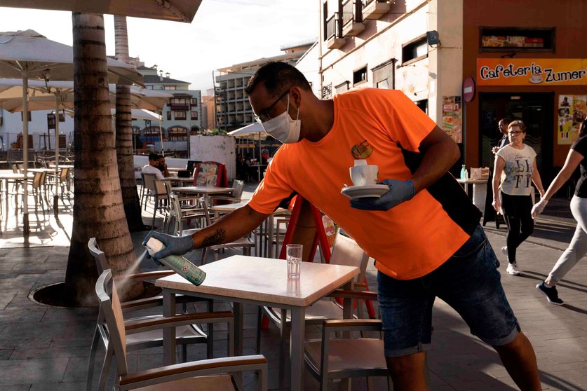 GRAFCAN5209. PUERTO DE LA CRUZ (TENERIFE) (ESPAÑA). Un camarero desinfecta unas sillas de una terraza de un bar de Puerto de la Cruz, en Tenerife.Canarias comienza este lunes la fase 1 del desconfinamiento y por ello está autorizado la apertura del pequeño comercio con restricción de aforo.EFE/Miguel Barreto