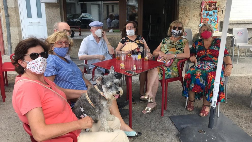 Un grupo de veraneantes disfrutan de un aperitivo en un bar de Cualedro. 
