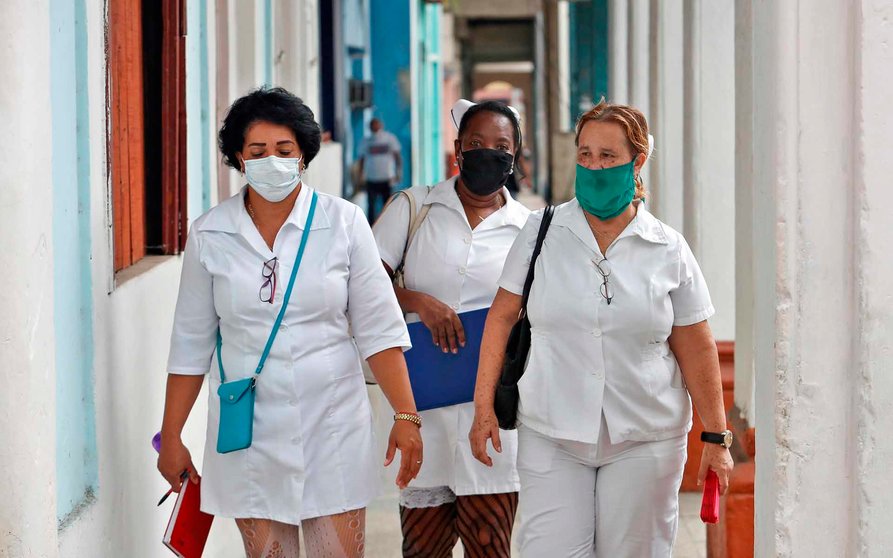 AME007. LA HABANA (CUBA), 08/10/2020.- Tres trabajadoras de la salud caminan por uno de los soportales de la ciudad hoy, en La Habana (Cuba). El gobierno cubano reportó este jueves 19 nuevos casos positivos al coronavirus, para un total de 5.917 diagnosticados. EFE/ Yander Zamora
