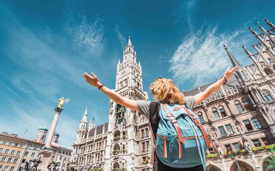 A girl tourist traveler enjoys a Grand view of the Gothic building of the Old town Hall in Munich. Sightseeing and exploration of Germany concept